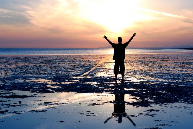 EMDR man with arms uplifted on beach